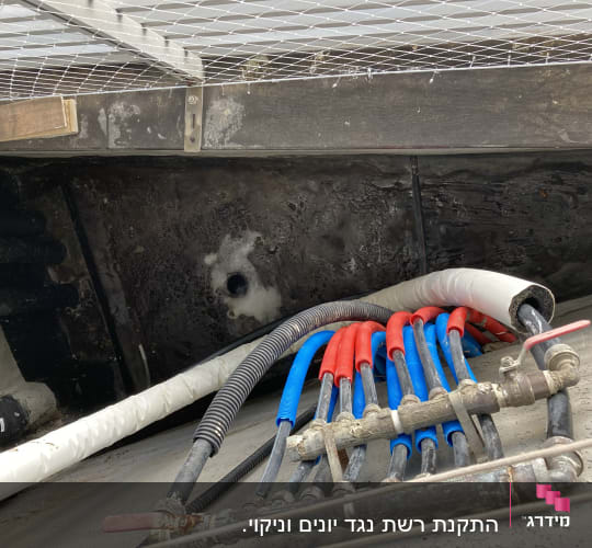 צינורות צבעוניים מתחת לרשת מתכת על קיר
